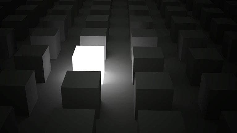 Rows of cubes in the darkness with a single cube lit up, shining while standing out of the crowd. - stock photo
