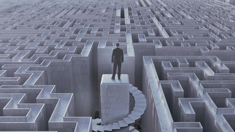 Businessman stranded at top of complex maze - stock photo